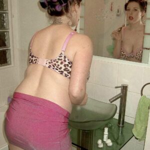 Brown-haired MILF models for a non-nude shoot in a mini-skirt while in a washroom and kitchen