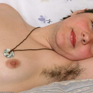 Hairy first-timer displays her hairy underarms and natural pussy on a bed