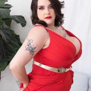 Tattooed BBW Nagini peels off a crimson dress while making her nude debut on a couch